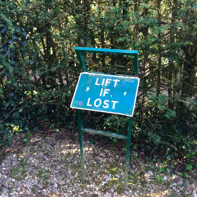 a blue sign next to a bush that says, lift if lost