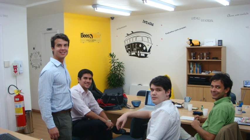 a few men are sitting around a desk