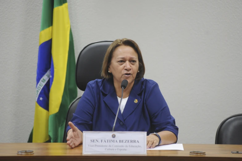 a woman sitting at a desk with her hands up to the microphone