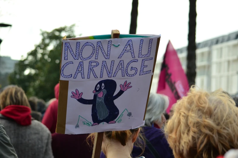 a woman holding a sign in the crowd with words on it