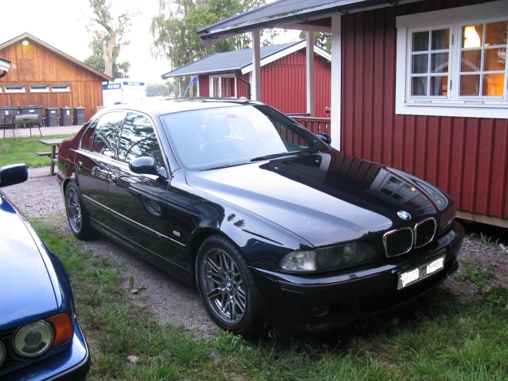 a black bmw parked next to a small house