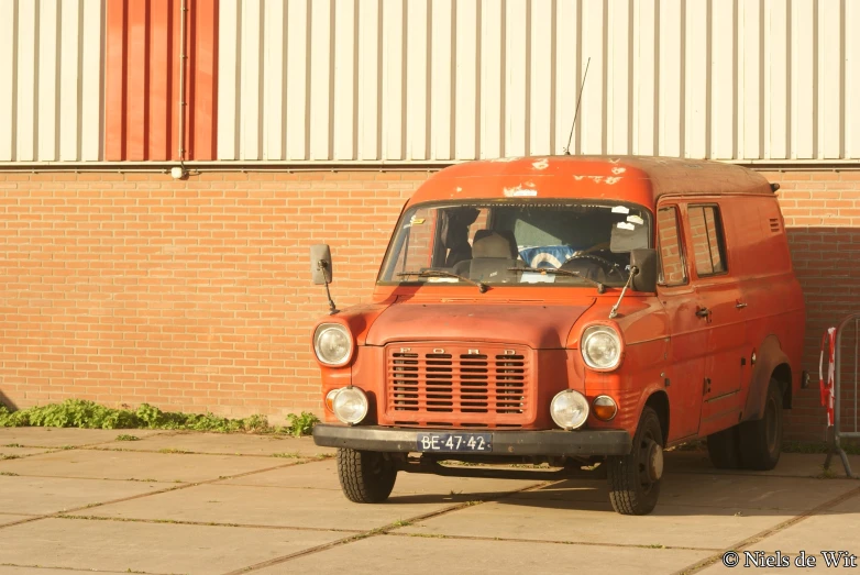 an orange van parked on the side of a brick building