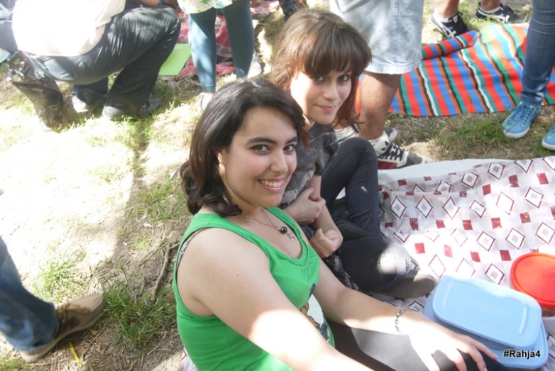 three people are sitting on the ground with coolers