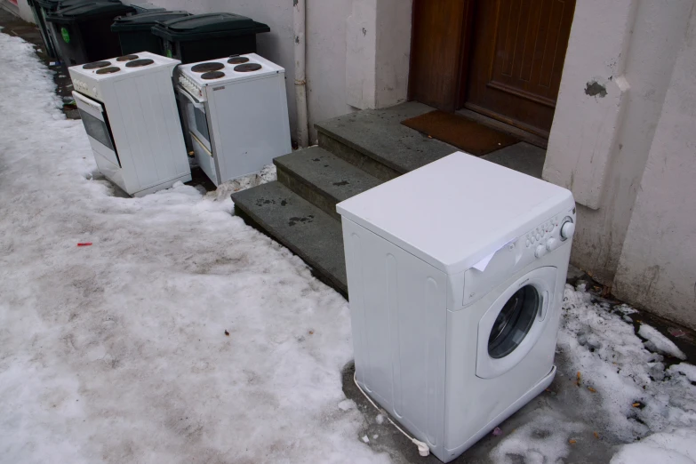several appliances are in snow beside an entryway