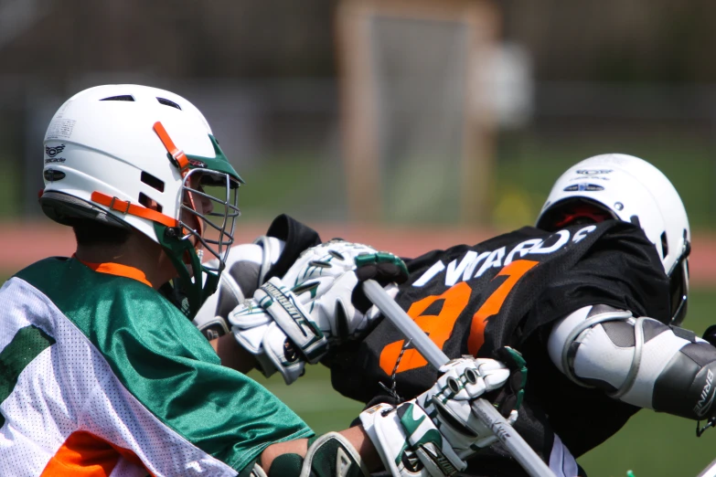 two players of lacrosse each in the air trying to block the ball