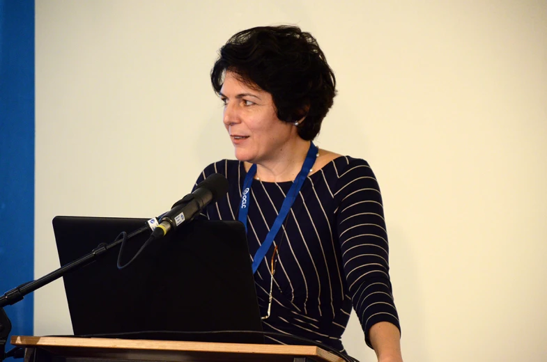 a woman stands at a podium behind a microphone