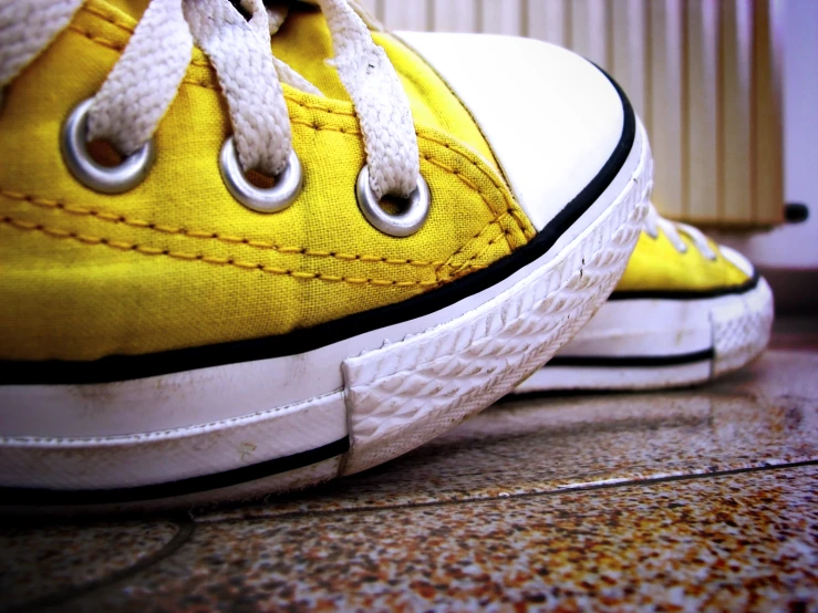 two yellow tennis shoes on top of a brown floor