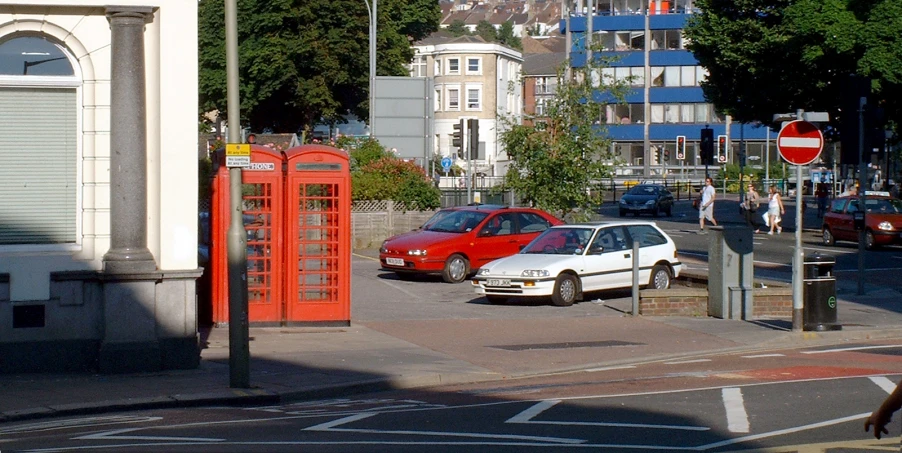 a car and a truck stopped at an intersection with telephone booths