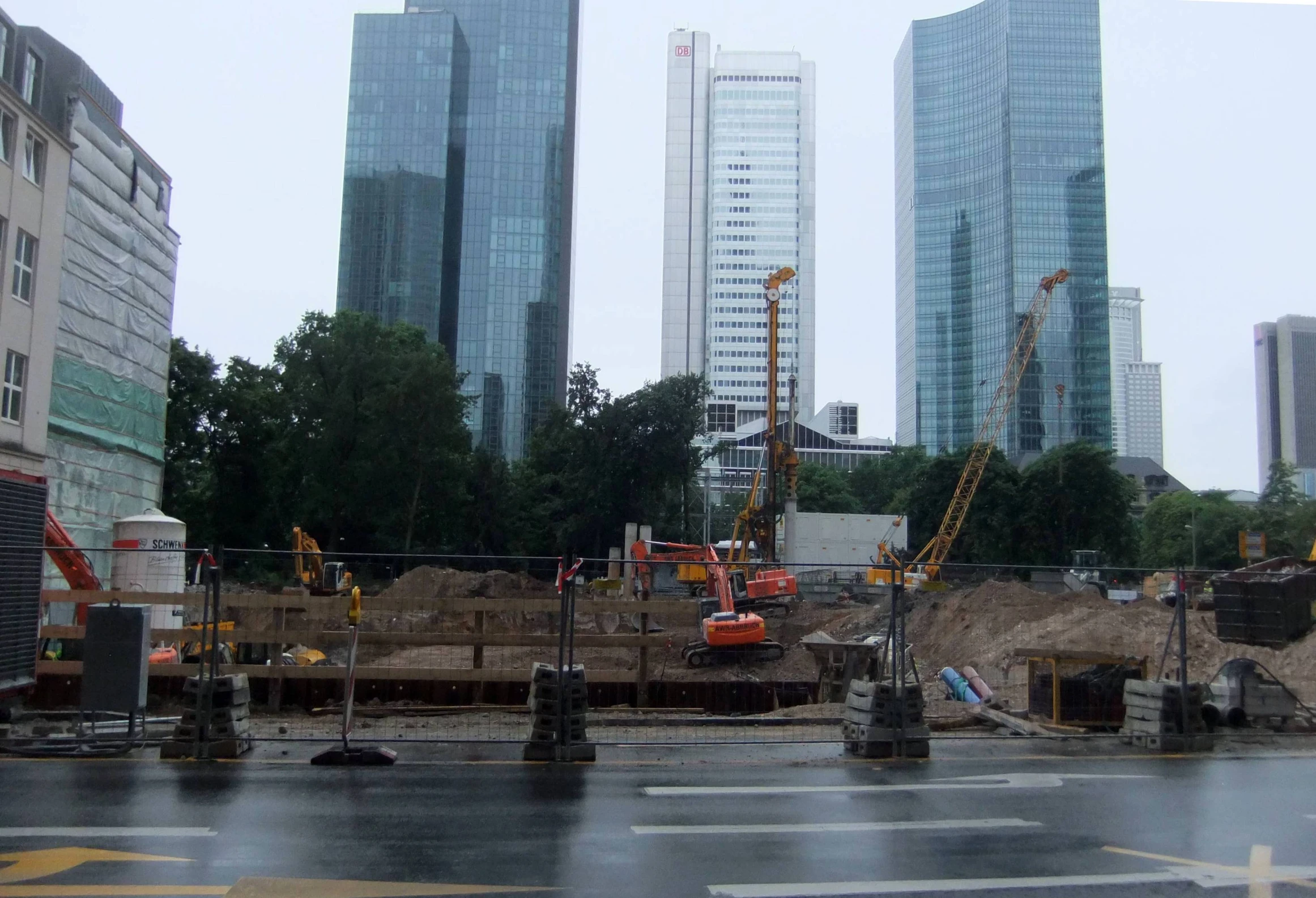 a construction site on a rainy day, with tall buildings in the distance