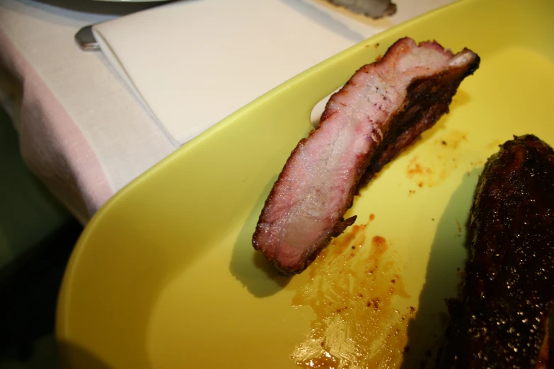 bacon is sitting on the side of a yellow plate