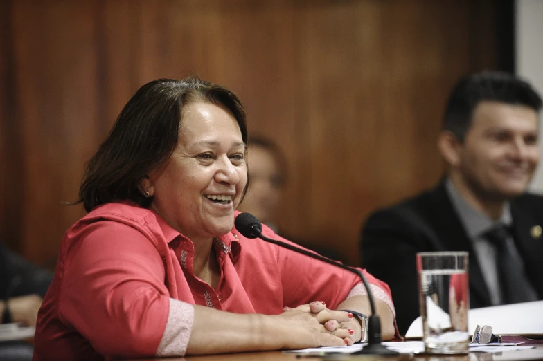 a woman is smiling while she speaks into a microphone