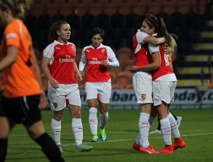 a group of women in uniform celeting on a soccer field