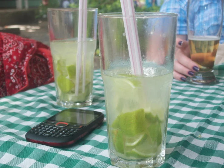 a ginnily drink with lime and a cell phone