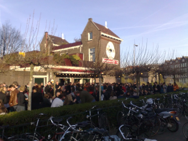 a group of people standing outside a building surrounded by bikes