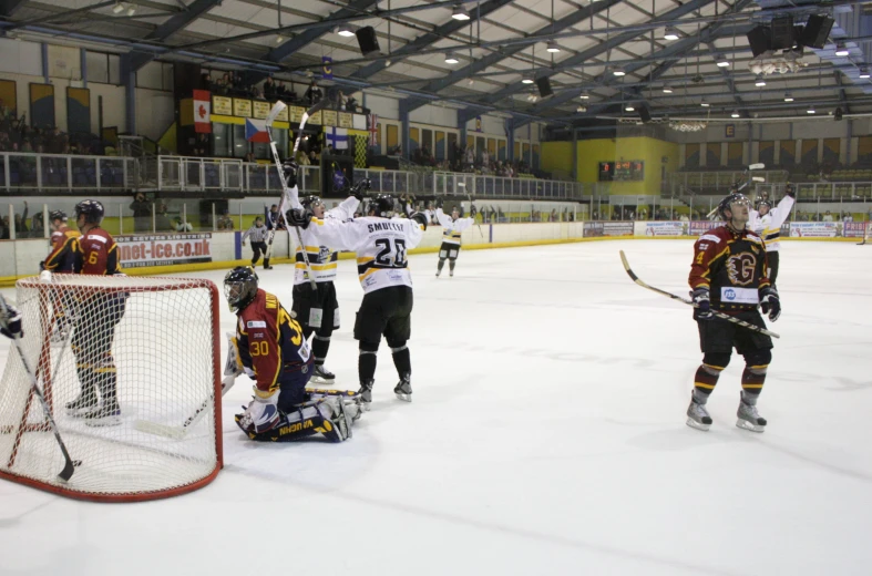 two men playing ice hockey with a goalie