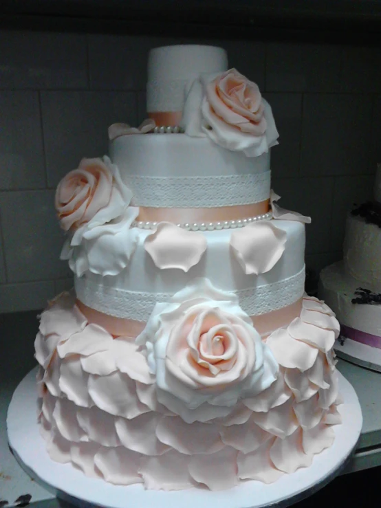the three tiered wedding cake has two large roses on top