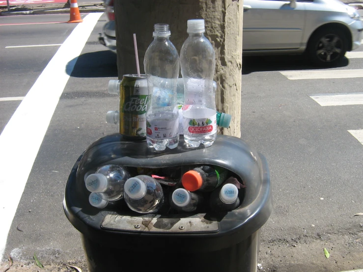 bottles of water and empty soda on top of a garbage can