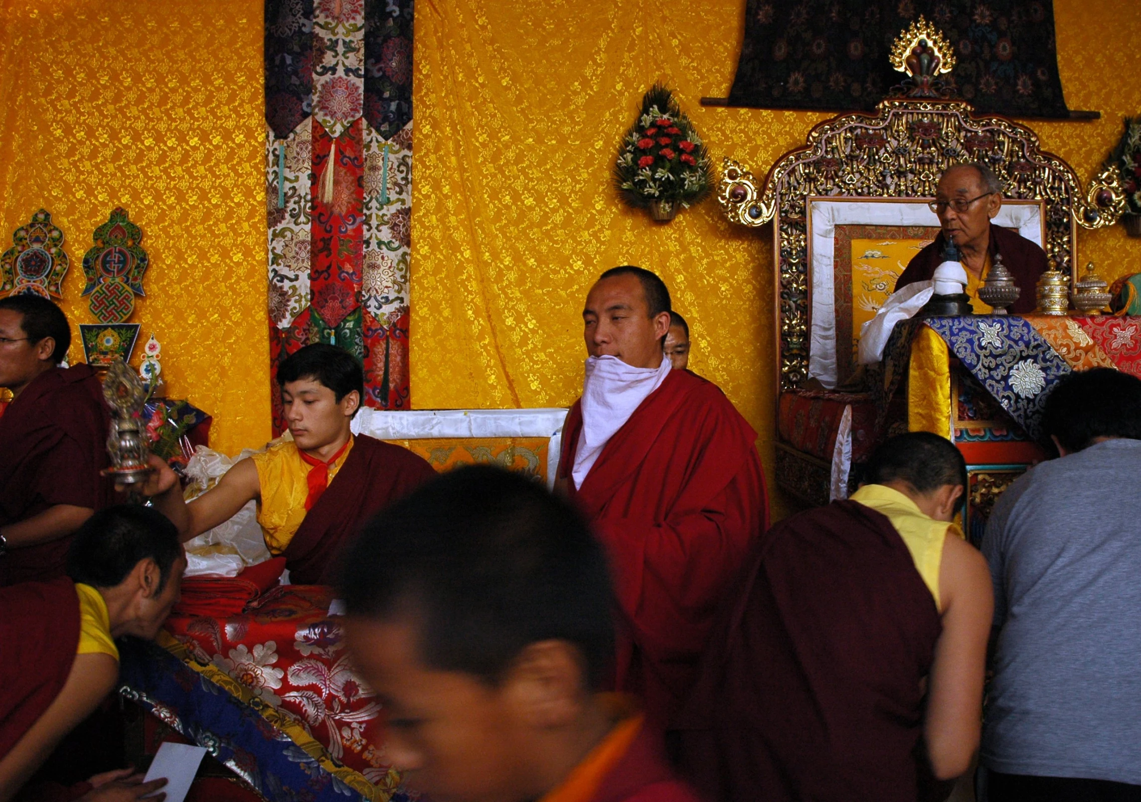 a group of monks is sitting in a yellow room