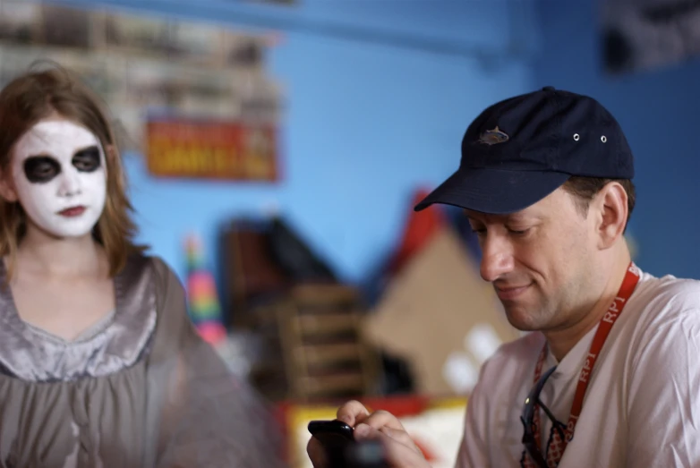 a man wearing makeup is holding a cell phone