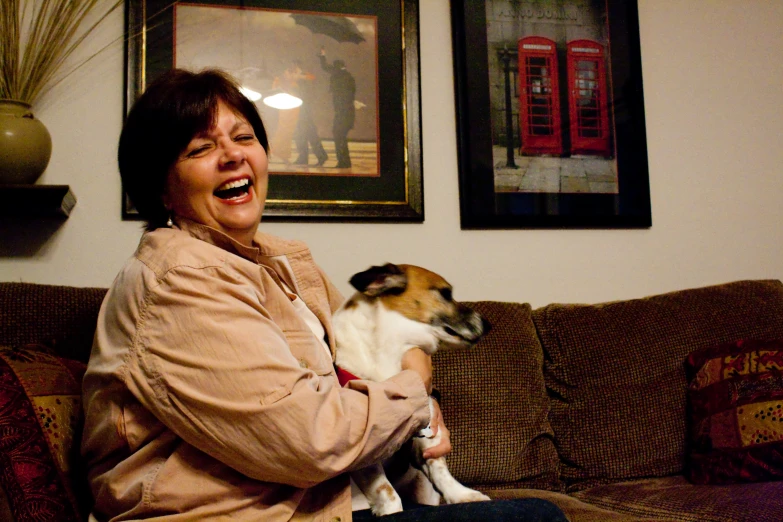 an older woman holding a dog and laughing