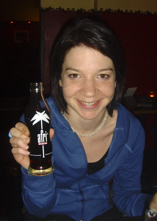 a smiling lady holding a bottle of soda