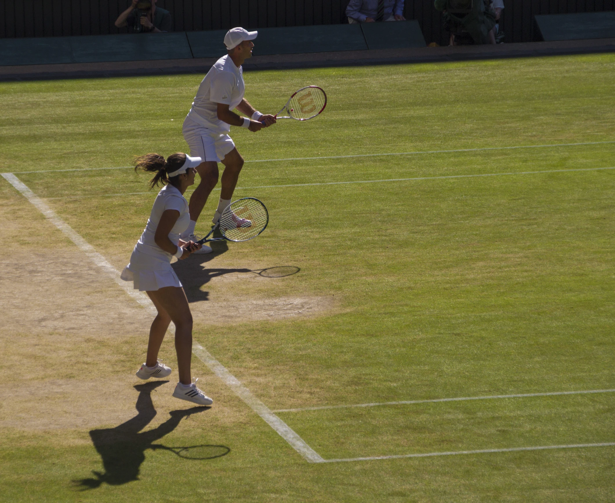 two women playing doubles tennis on a grass court