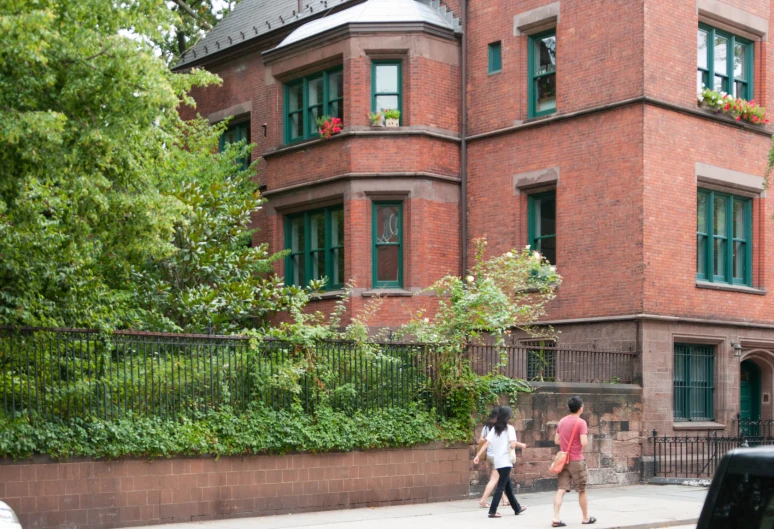 a couple walking by a brick building on a sidewalk