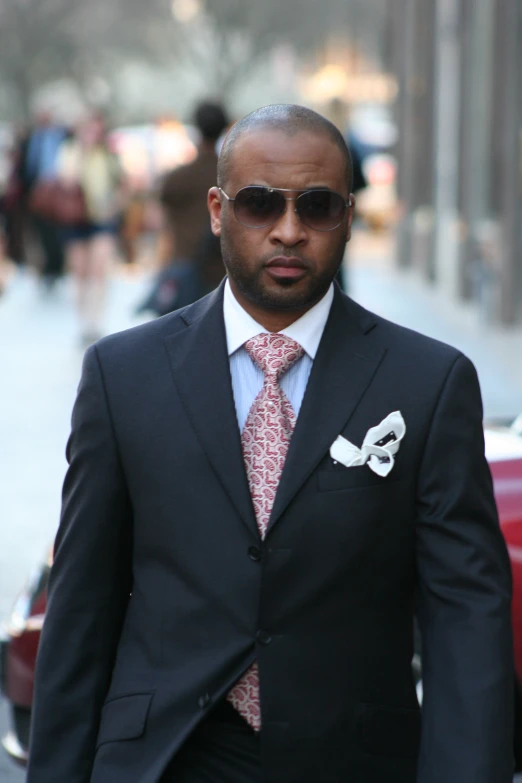 an african american man in sunglasses and suit on a city street