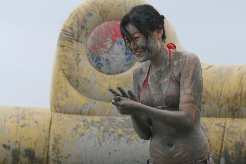 a woman covered in white mud is holding a cell phone