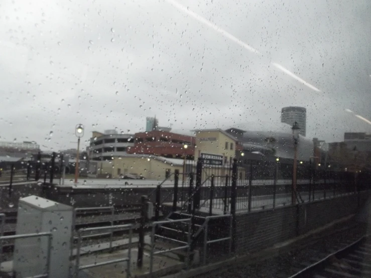 a train view out the window of a rainy looking station