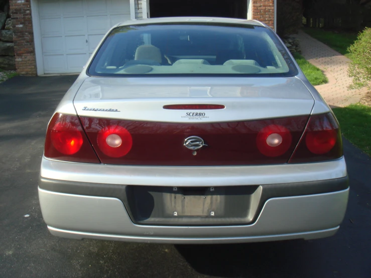 a silver sedan parked in a driveway next to a garage