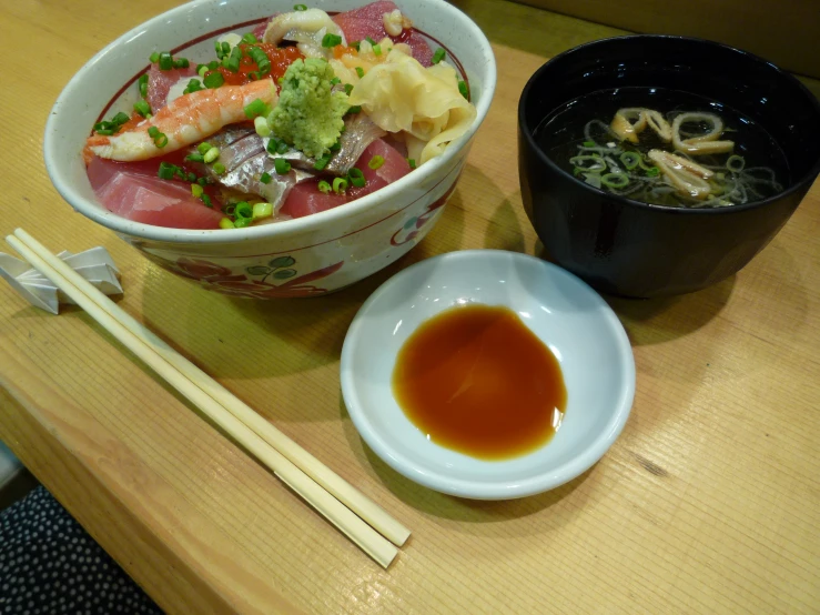 a plate of ramen sits next to a bowl of soup with chop sticks