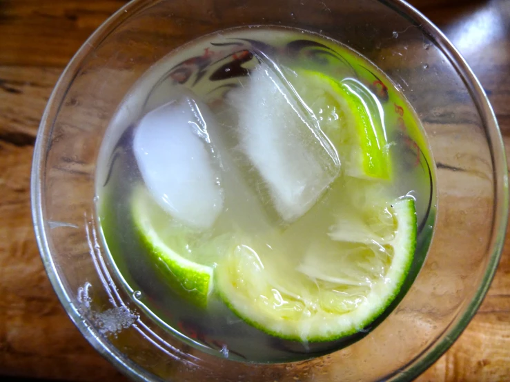 a drink with ice and lime in a glass on a wooden table