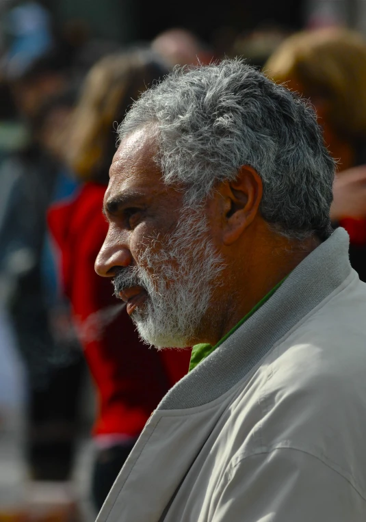 an old man wearing a white beard stands in the street