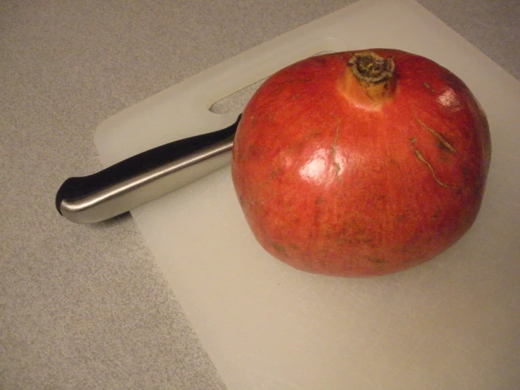 an apple and knife on a  board with a gray counter