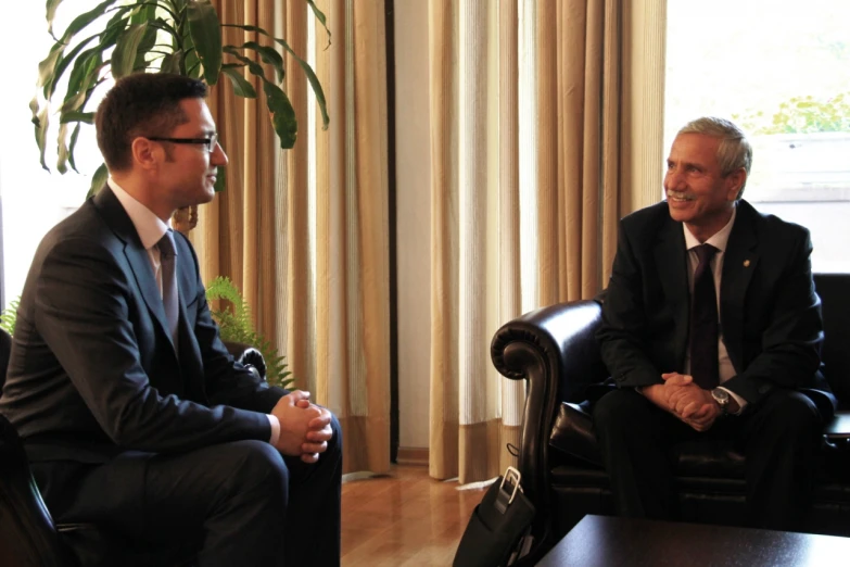 two men sitting in chairs facing each other