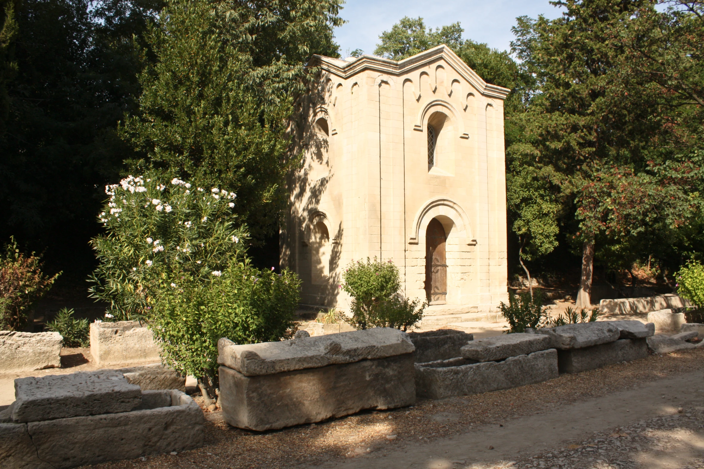 a stone church surrounded by trees and bushes