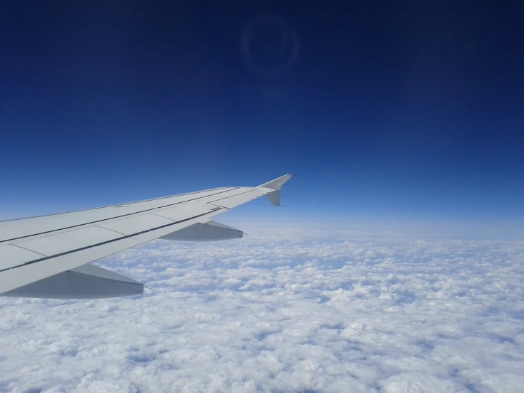 the wing of a plane flying over some clouds