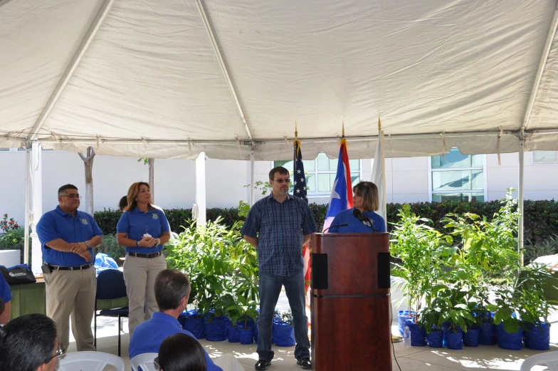 people standing at a podium while others stand nearby in front of the stage