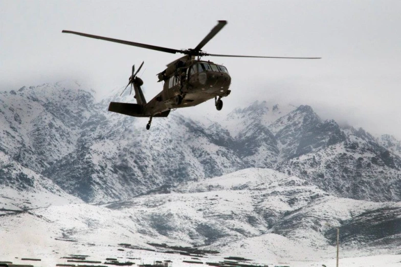 a helicopter flies over mountains in the snow