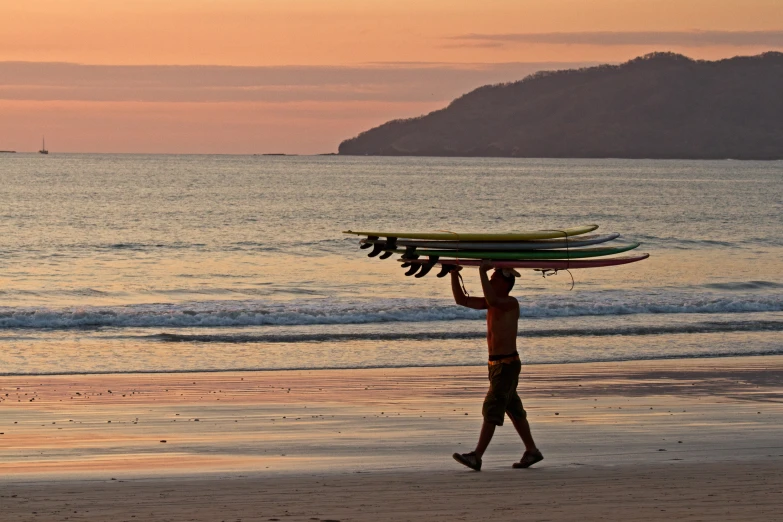 a man holding a tray on top of his head while walking down a beach