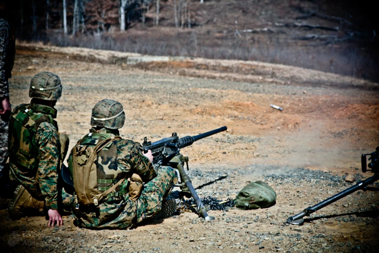 two men in camouflages, one is holding a machine gun