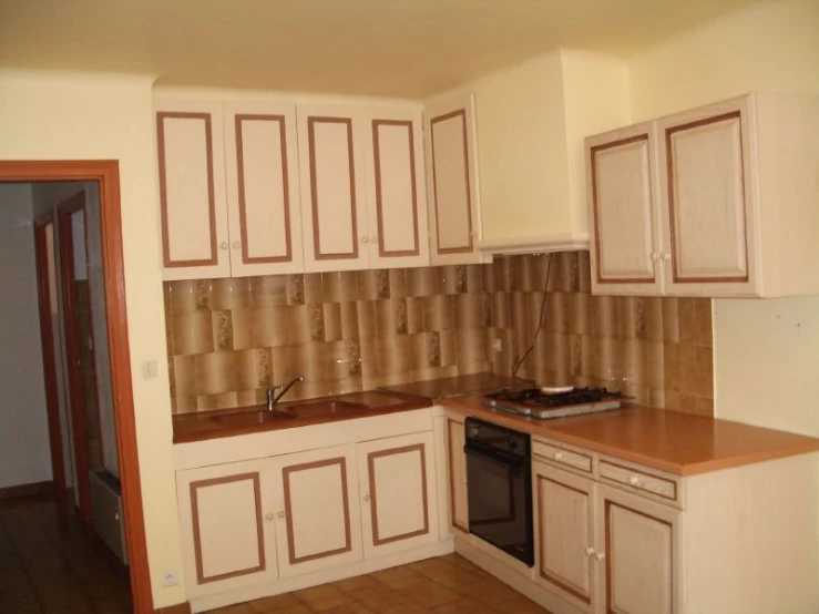 an empty kitchen with tan cabinets and a dishwasher