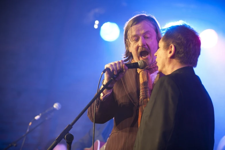 the two men are singing into a microphone