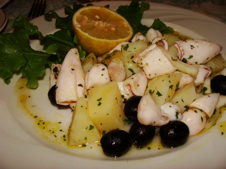 a close up view of chicken and potatoes on a white plate with a lime