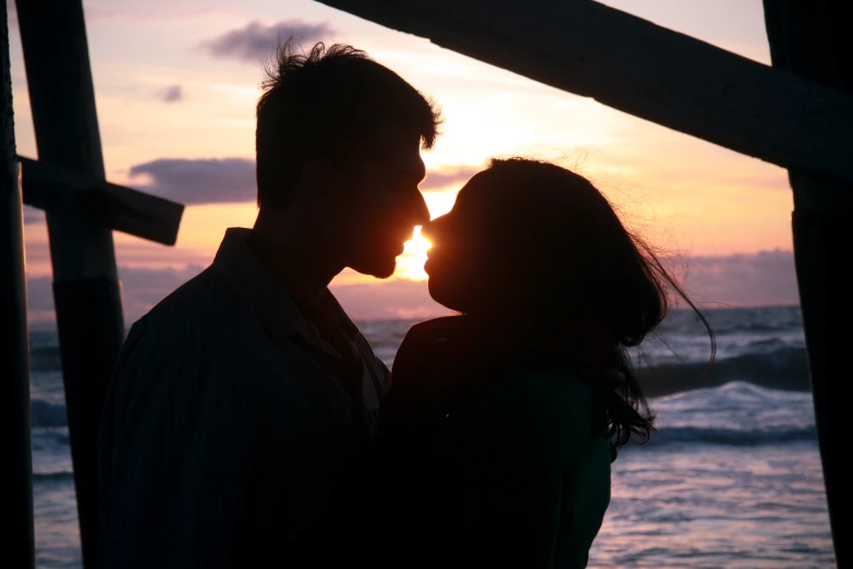 a man and a woman are kissing in front of the sunset