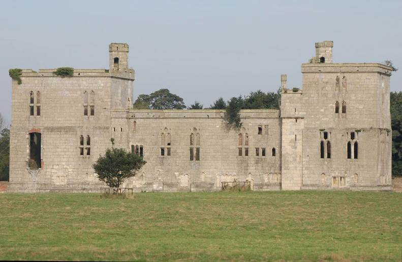 a stone building in a green field with a tree