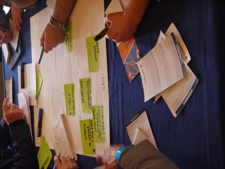 a group of people sitting around a table writing on paper