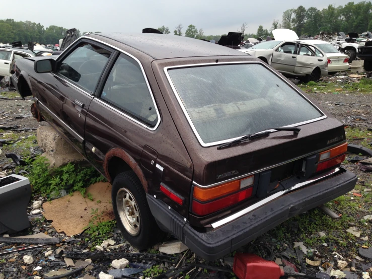 an old rusty car sits in a junk yard