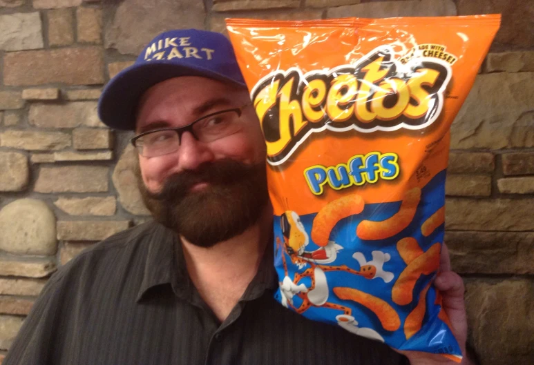 a man holding a bag of cheese puffs with the cap on